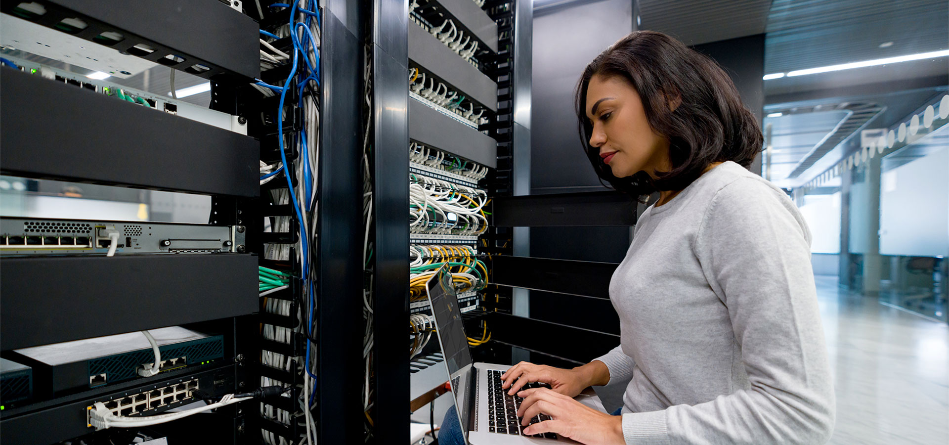 A technician working at network racks in a data center.
